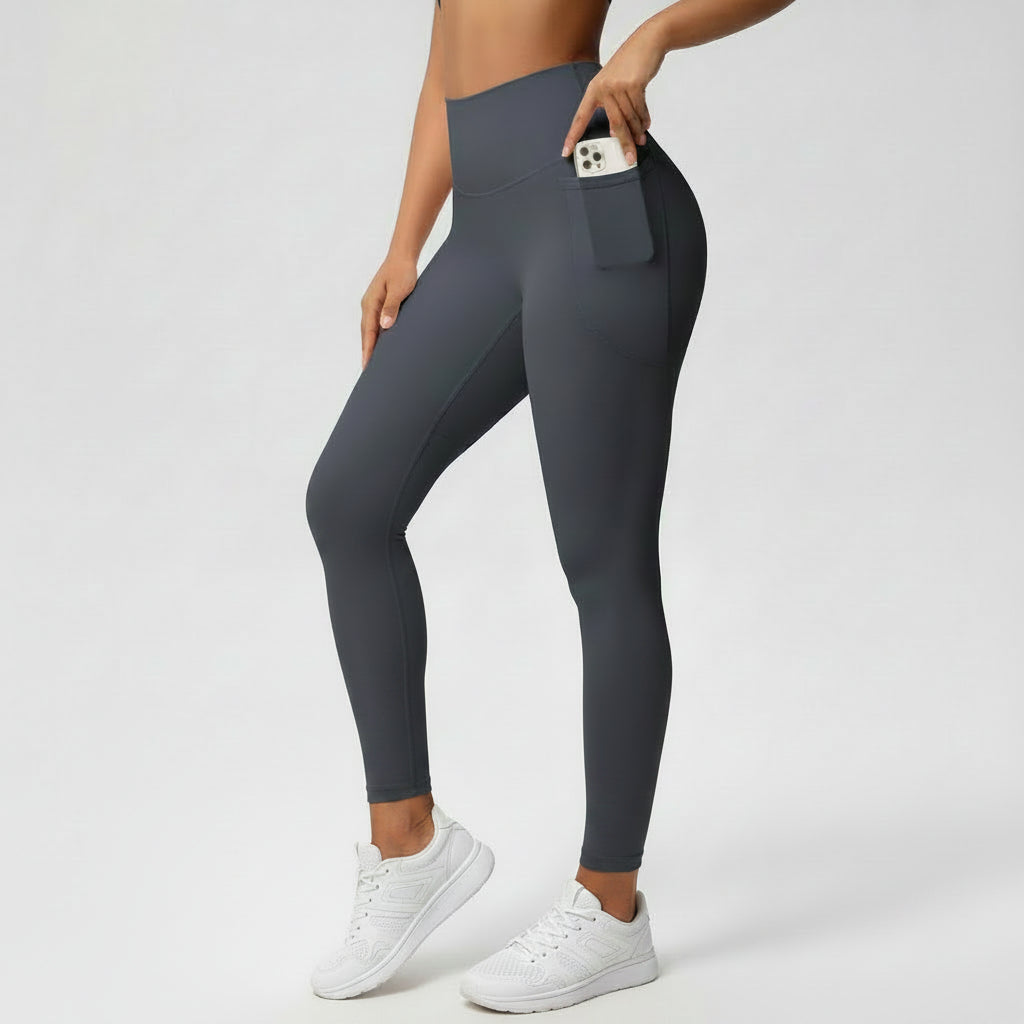 Person wearing dark gray leggings with a pocket on a light gray background